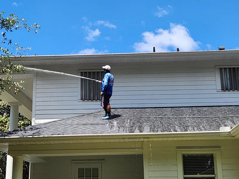 Technician pressure washing home siding to remove mold